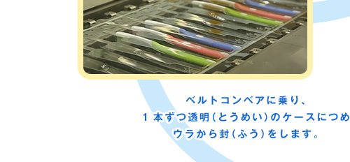 ベルトコンベアに乗り、1本ずつ透明（とうめい）のケースにつめウラから封（ふう）をします。